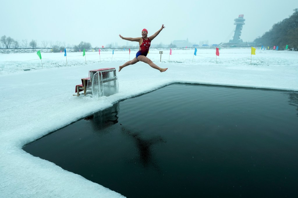 Winter swimmer leaping into an ice pool on the frozen Songhua River in Harbin