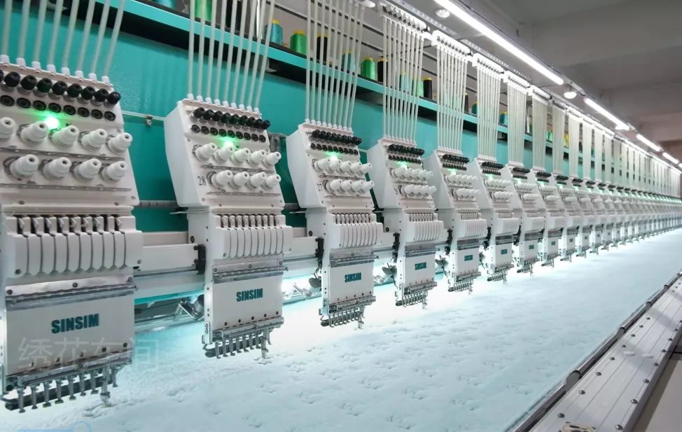 Row of industrial multi-head computerised embroidery machines in the plush factory