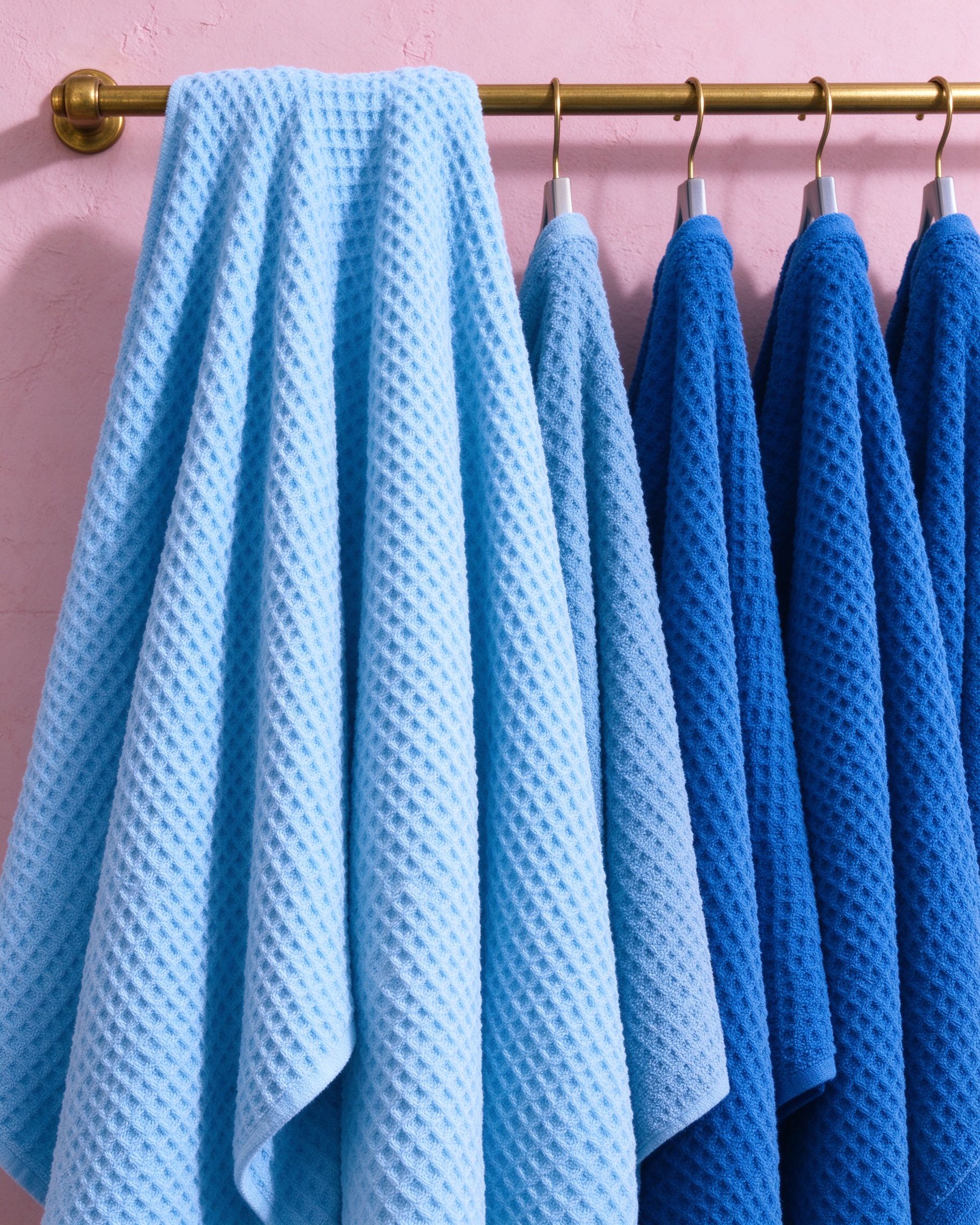 Gradient blue waffle weave towels hanging on brass rail