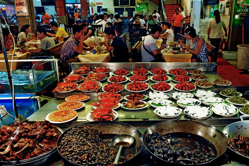 Trays of prepared dishes on a Nanning night market street
