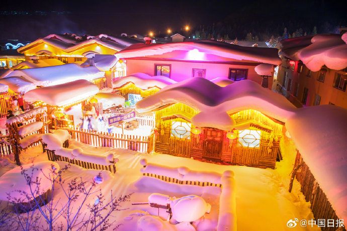 Snow-covered log houses with red lanterns at China Snow Town at night