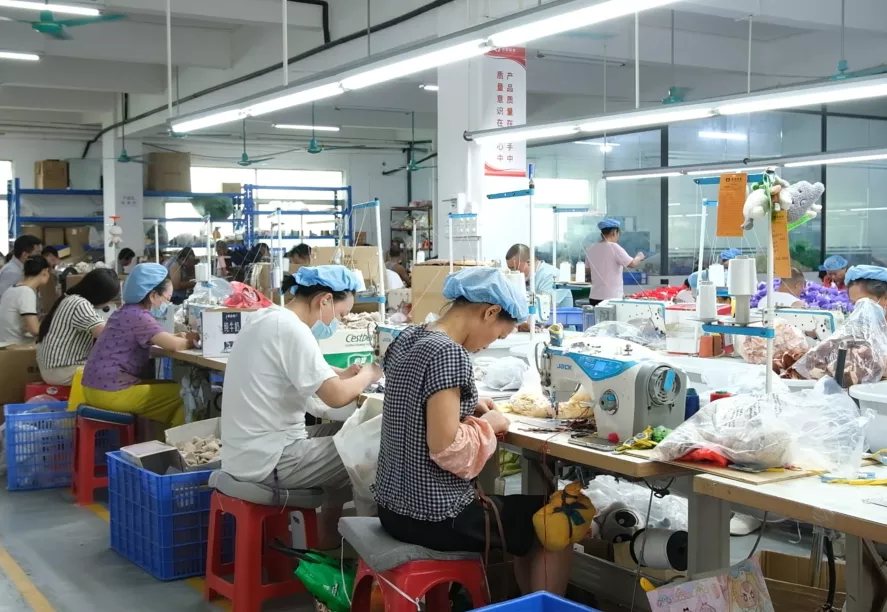 Workers sewing plush toys at sewing machines in the Guaila Toys workshop